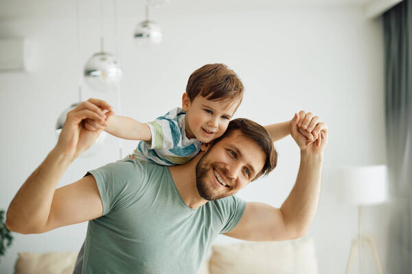 Playful little boy and his father having fun together at home. 
