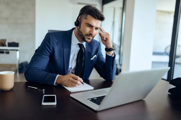 Young Businessman Writing Notes While Having Conference Call Laptop Office — Stock Fotó