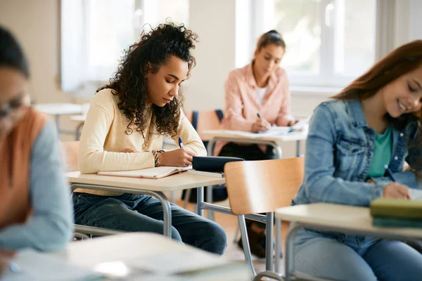 African American high school student taking notes during lecture in the classroom. 