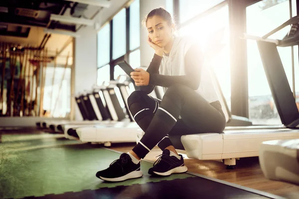 Sad Athletic Woman Using Mobile Phone Thinking Something Sports Training — Stockfoto