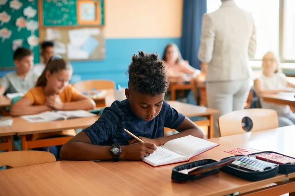 Black Schoolboy Writing His Notebook Class Classroom —  Fotos de Stock