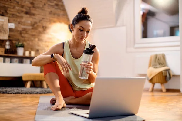 Female Athlete Surfing Net Laptop While Drinking Water Working Out — Φωτογραφία Αρχείου