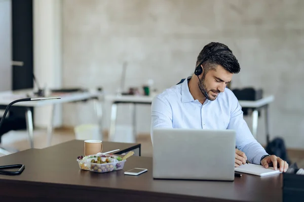 Young Businessman Headset Using Computer Writing Notes While Working Office — стоковое фото