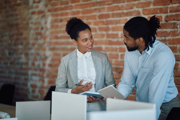 Black entrepreneurs talking to each other while corporate office. Focus is on businesswoman.