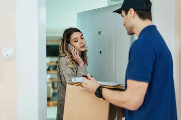 Young Woman Talking Mobile Phone While Receiving Home Delivery Form — Stok Foto