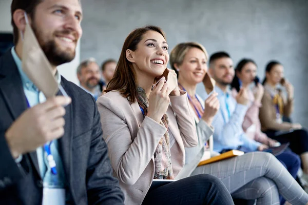 Large group of business people feeling safe and taking off their protective face mask at the end of COVID-19 pandemic.