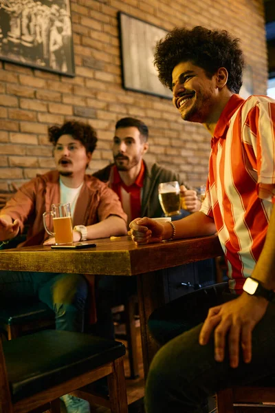 Multiracial group of sports fans watching a match on TV in a pub. Focus is on Muslim man.