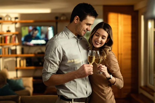 Smiling Couple Embracing While Toasting Champagne Home — стоковое фото