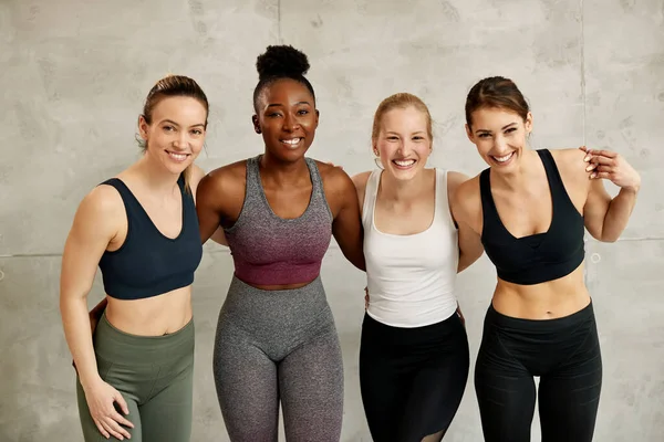 Portrait Happy Diverse Athletic Women Standing Embraced Wall Looking Camera — Stock Photo, Image