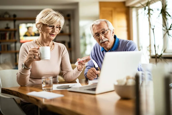 Mature couple analyzing their financial bill while paying them over computer at home.