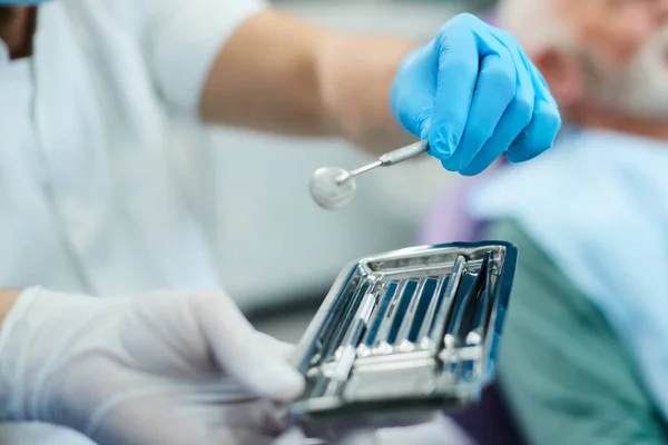 Close-up of stomatologist using angled mirror during dental examination at dentist\'s office.