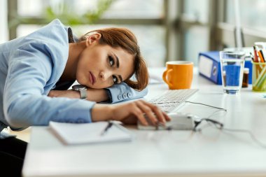 Pensive businesswoman feeling bored and resting at her office desk. 