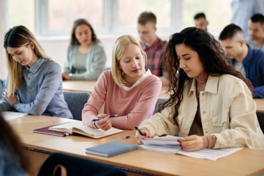 Female college students cooperating while studying together in the classroom.
