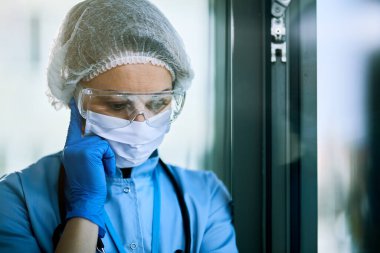 Pensive nurse feeling worried while working at the hospital during COVID-19 pandemic. 