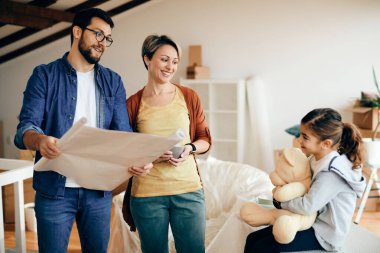 Happy family communicating while examining housing plans after relocating into a new home. 