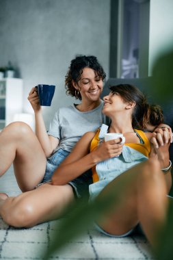 Kahve içerken ve evde dinlenirken el ele tutuşan genç bir çift..