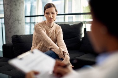 Genç üzgün kadın doktorun muayenehanesinde psikoterapistle görüşüyor.. 