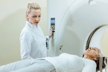 Female radiologist and mature patient during MRI scanning procedure in the hospital. 