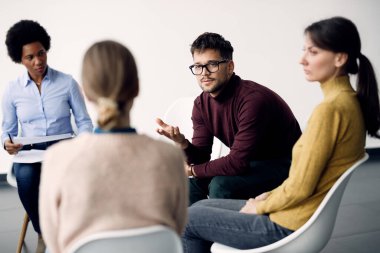 Young man talking while attending group therapy at medical center. 