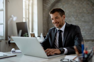Happy businessman using laptop while working in the office. 