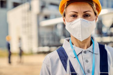 Portrait of female civil engineer with protective face mask looking at camera.
