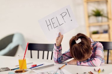 Small girl feeling desperate and holding HELP sing while homeschooling during virus epidemic. 