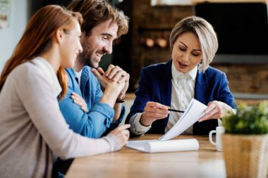 Real estate agent and young couple going through lease agreement while having a meeting at home. 