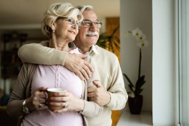 Mutlu olgun çift kucaklaşırken evde pencerenin kenarında hayal kuruyor.. 