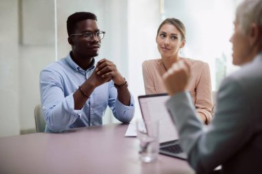 African American man and his wife talking to their financial advisor on a meeting in the office.