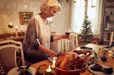 Mature woman setting the table for family lunch on Thanksgiving. 
