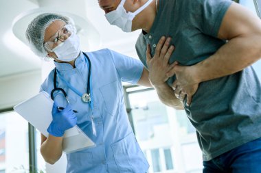 Female doctor with a patient who is complaining of chest pain during coronavirus epidemic. 