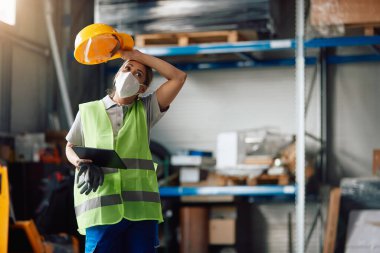 Female worker using touchpad and feeling tired after working at distribution warehouse during coronavirus pandemic.