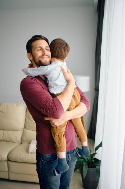 Young father enjoying with his son and embracing him at home.