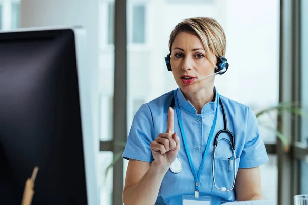 Female healthcare worker communicating with patient and looking at camera while working at medical call center.