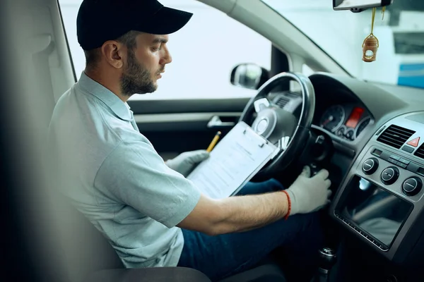Genç oto tamircisi atölyede çalışırken arabayı çalıştırıyor.. 
