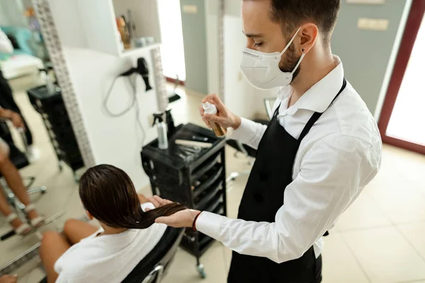 Young Hairdresser Wearing Protective Face Mask While Treating Woman Hair — Fotografia de Stock