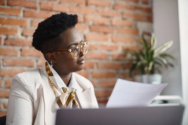 African American female entrepreneur analyzing business reports while working at corporate office.