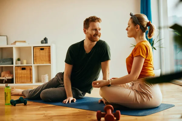 Zen-like woman practicing Yoga in lotus pose while husband is looking at her at home.