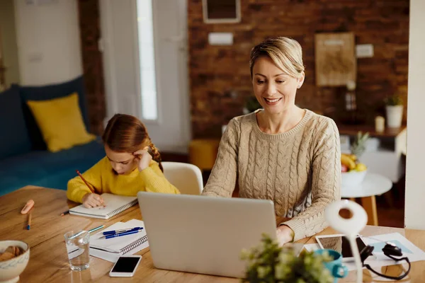 Happy Mother Working Laptop While Her Small Daughter Doing Homework — Φωτογραφία Αρχείου