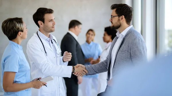 Male Doctor Handshaking Businessman While Meeting Hallway Medical Clinic — Stockfoto