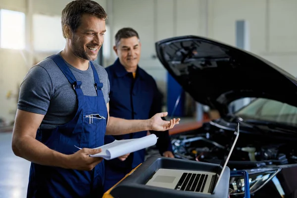 Happy Mechanic Using Laptop While Doing Car Diagnostic His Colleague — ストック写真