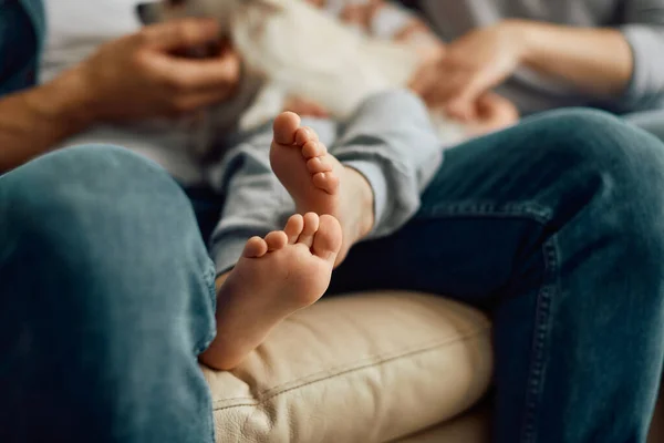 Close-up of family spending time together at home. Focus is on boy's feet.