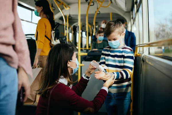 Little Boy Face Mask Using Hand Sanitizer While Commuting Public 免版税图库照片