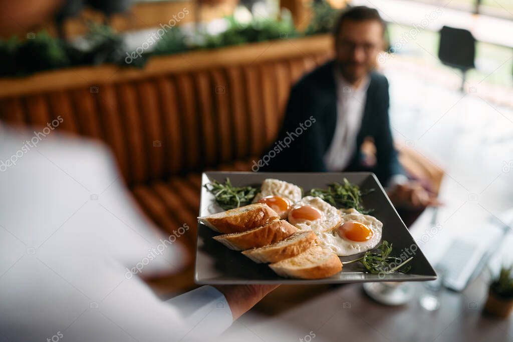 Close-up of waitress serving sunny side up eggs for breakfast in a cafe