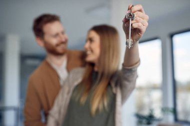 Close-up of couple holding house key while relocating into new home.