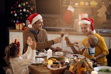 Mutlu bir aile Noel yemeği yerken ve yemek odasında kadeh kaldırırken eğleniyor.. 