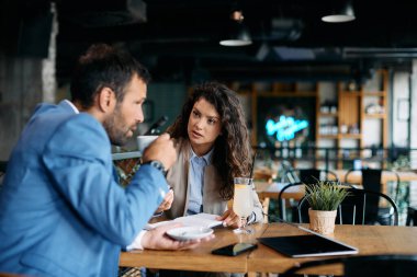 Female entrepreneur and her coworker communicating during business meeting in a cafe.