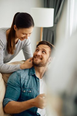 Happy man and his wife communicating while relaxing at home. 