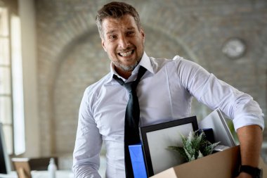Businessman feeling depressed while holding box of his belongings after being fired from work. 