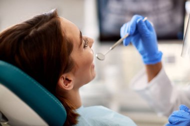 Close-up of woman having her teeth examined during dental appointment at dentist's office.
